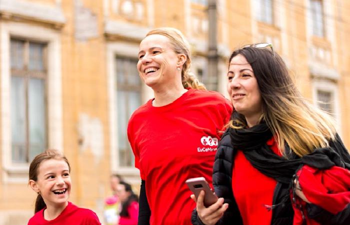Three women in red shirts walking together, promoting SMS fundraising efforts.